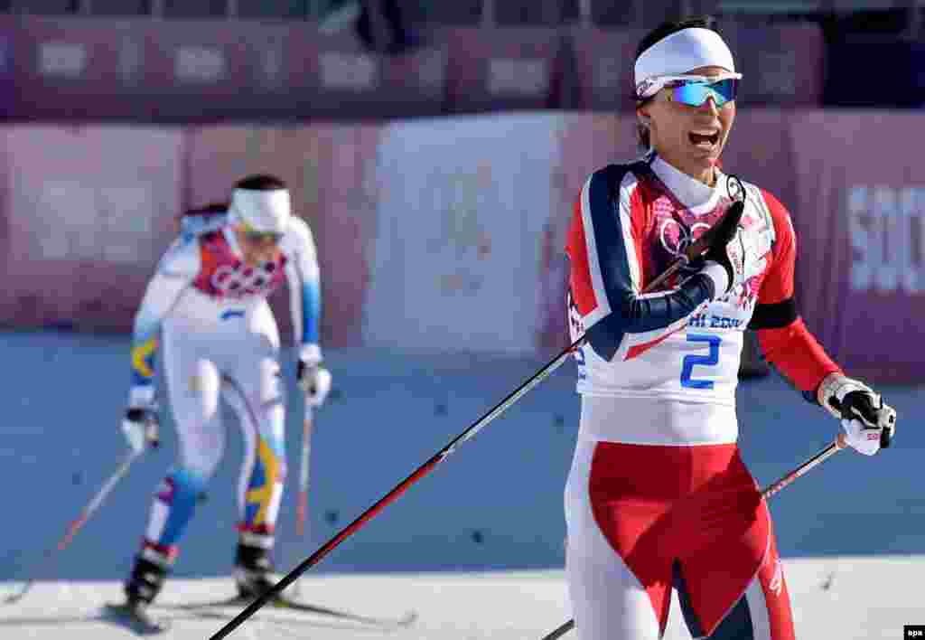 Marit Bjoergen of Norway (right) celebrates winning the gold medal in the women's 7.5 kilometer + 7.5 kilometer skiathlon competition.