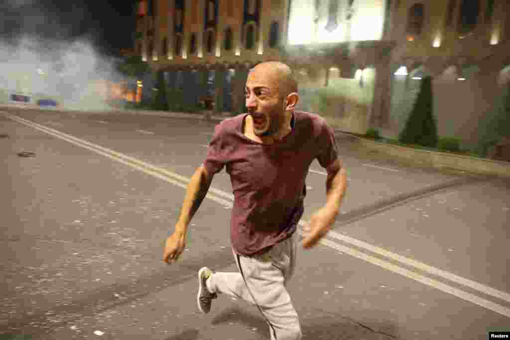 A man flees as police fire tear gas.&nbsp;