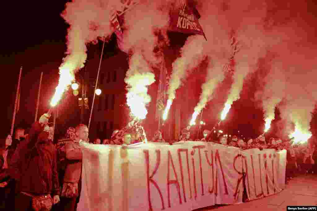 Ukrainian nationalists protesters burn flares and hold a banner reading &quot;No to capitulation&quot; during their protest against approval of so-called Steinmeier Formula in front of the presidential office in Kyiv on October 1. (AFP/Genya Savilov)