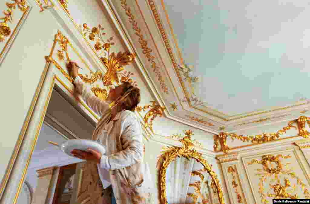 Мастер подкрашивает золотой краской декоративное оформление двери одной из комнат виллы, 11 июня