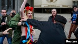 Ukraine -- Members of Crimean self-defence units block a topless activist from the Ukrainian feminist group Femen, who is taking part in an anti-war protest near the Crimean parliament building in Simferopol, March 6, 2014.