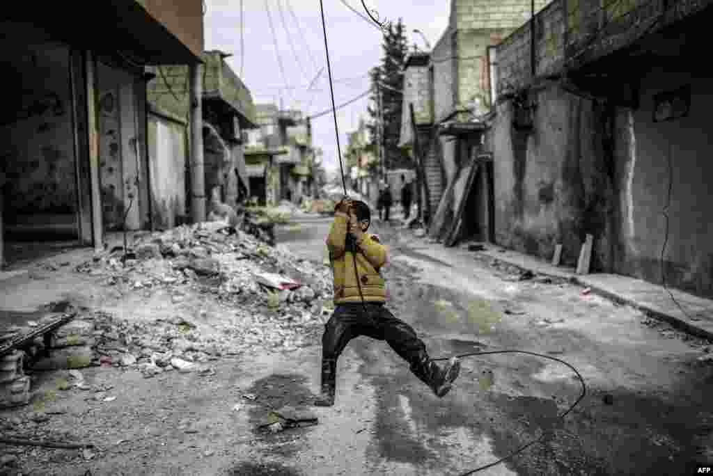 A Kurdish Syrian boy plays among destroyed buildings in the town of Kobani on March 24. (AFP/Yasin Akgul)