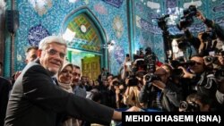 The head of Iran's reformist coalition in parliamentary elections Mohammad Reza Aref (c) shows his inked finger after casting his ballot at a polling station in Tehran, February 26, 2016. FILE PHOTO