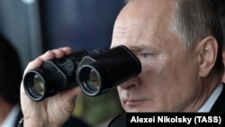 Президент России Владимир Путин смотрит в бинокль во время военных учений
