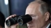 Ресей президенті Владимир Путин әскери жаттығу кезінде бинокльмен төңіректі шолып отыр. 