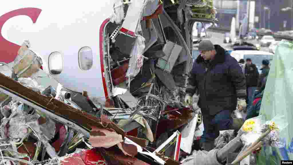 A Russian recovery worker walks among aircraft debris next to a highway near Moscow's Vnukovo Airport after a plane crash that killed four people. (Reuters/Mikhail Voskresensky)
