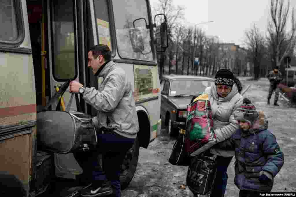 People board a bus to leave the town.