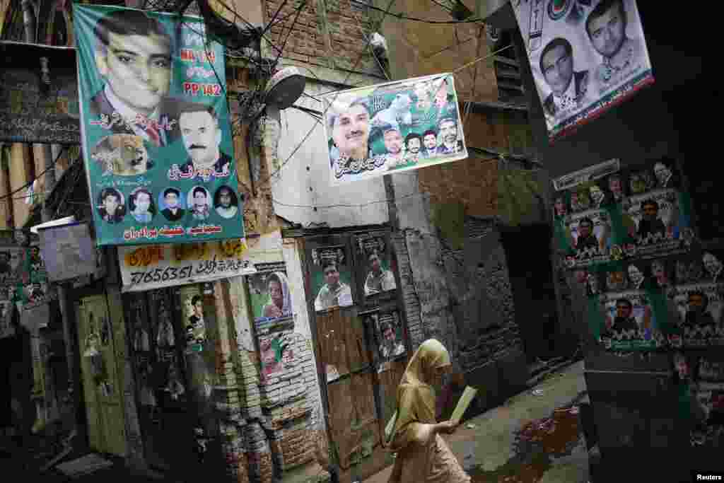 A girl walks in the old part of Lahore decorated with election posters. (Reuters/Damir Sagolj)