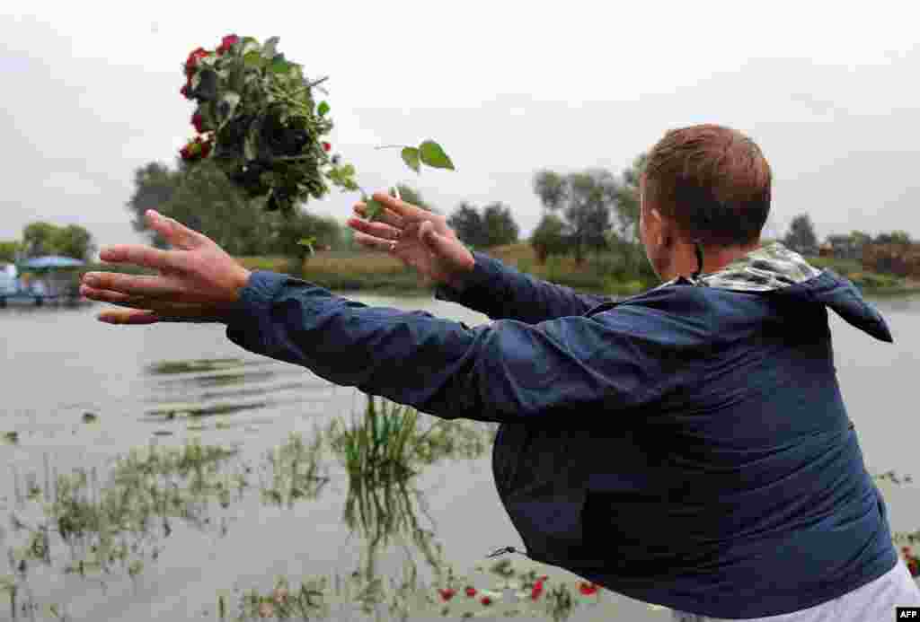 A man throws flowers at the plane crash site beside the Tunoshna River.