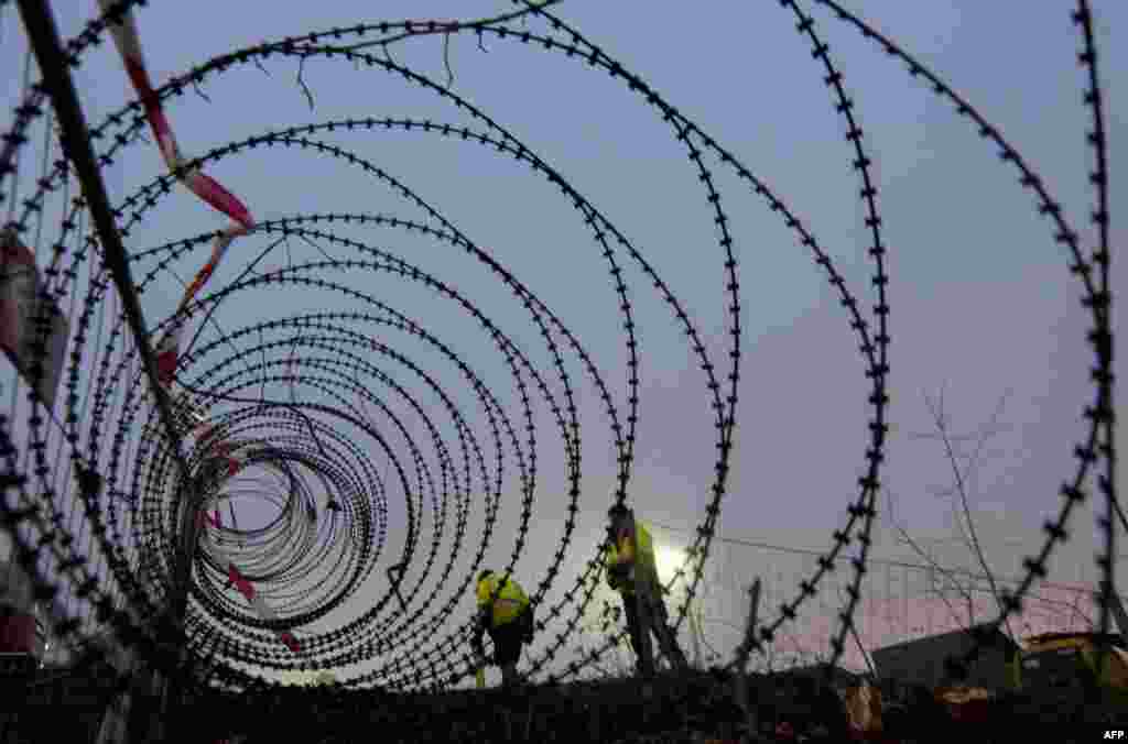 Workers take meassurements of a near-finished section of a 3.7-kilometer-long fence at a border crossing between Austria and Slovenia at Spielfeld. (AFP/Joe Klamar)