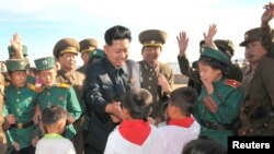 Disa fëmijë duke përshëndetur liderin verikorean Kim Jong Un.