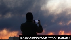 Людина фотографує, поки дим піднімається після вибуху у Тегерані, Іран, 3 березня 2026 року