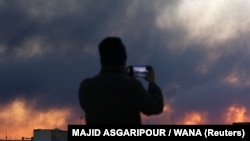 A person records smoke rising following an explosion in Tehran on March 3.