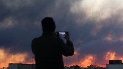 A person records smoke rising following an explosion after Israel and the United States launched strikes in Tehran on March 3.