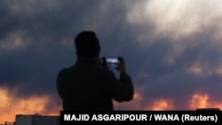 A person records smoke rising following an explosion after Israel and the United States launched strikes in Tehran on March 3.