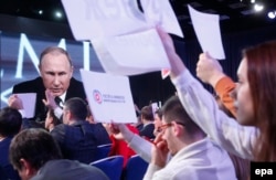 Journalists use signs and other methods to try to get Putin's attention and ask a question.