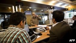 An Iranian customer speaks with a bank clerk at the Export Development Bank of Iran in the capital Tehran on July 27, 2015. AFP PHOTO / BEHROUZ MEHRI 