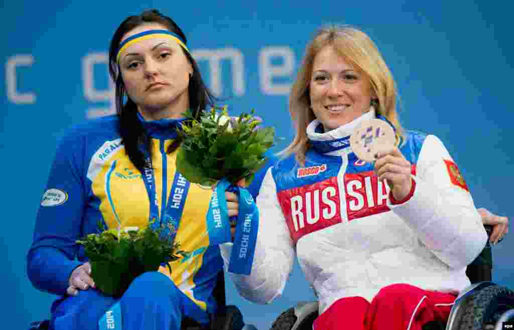 Svetlana Konovalova of Russia (right) proudly displays her bronze medal at the Paralympic Winter Games in Sochi as Ukrainian gold medalist Lyudmyla Pavlenko looks on stoically. (epa/Julian Stratenschulte)