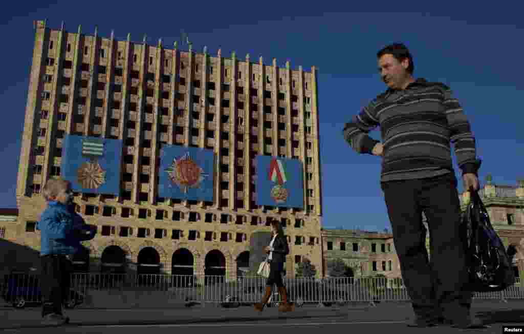 People pass by the Council of Ministers of Abkhazia building in Sukhumi, the capital of the breakaway Georgian region. The building was destroyed in the 1992-93 war with Georgia.