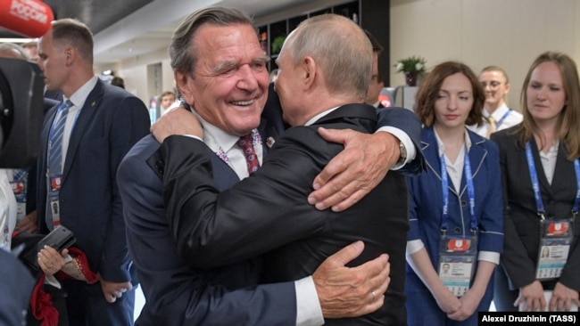Президентът на Русия Владимир Путин прегръща Герхард Шрьодер, председател на Комитета на акционерите на "Северен поток 2" и бивш канцлер на Германия, на откриването на Световното първенство по футбол през 2018 г. на стадион Лужники.