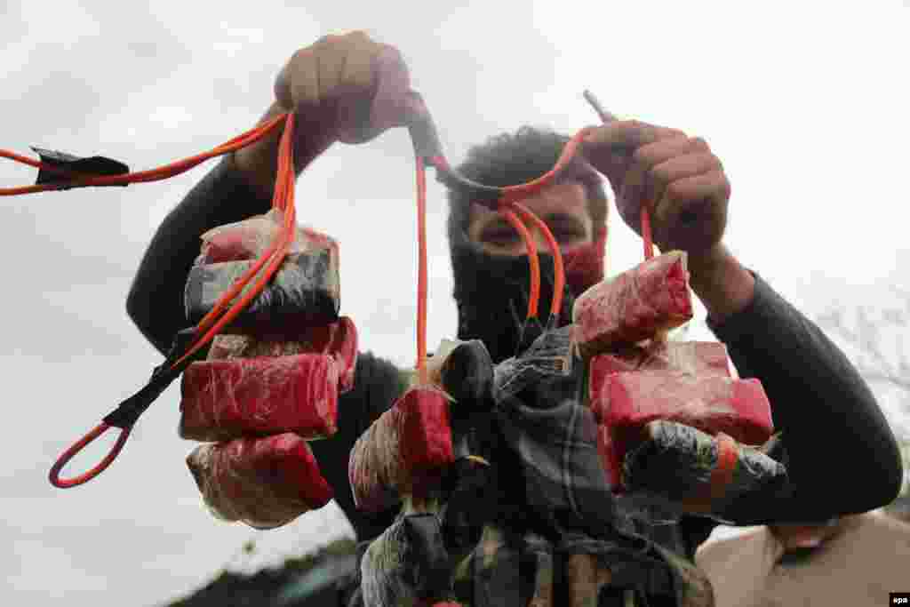 An Afghan Army soldier shows a diffused bomb used at the scene of a suicide bomb attack that targeted the Indian consulate in Jalalabad, Afghanistan. Three suicide attackers detonated their car bomb, killing eight children and an adult. (epa/Abdul Mueed)