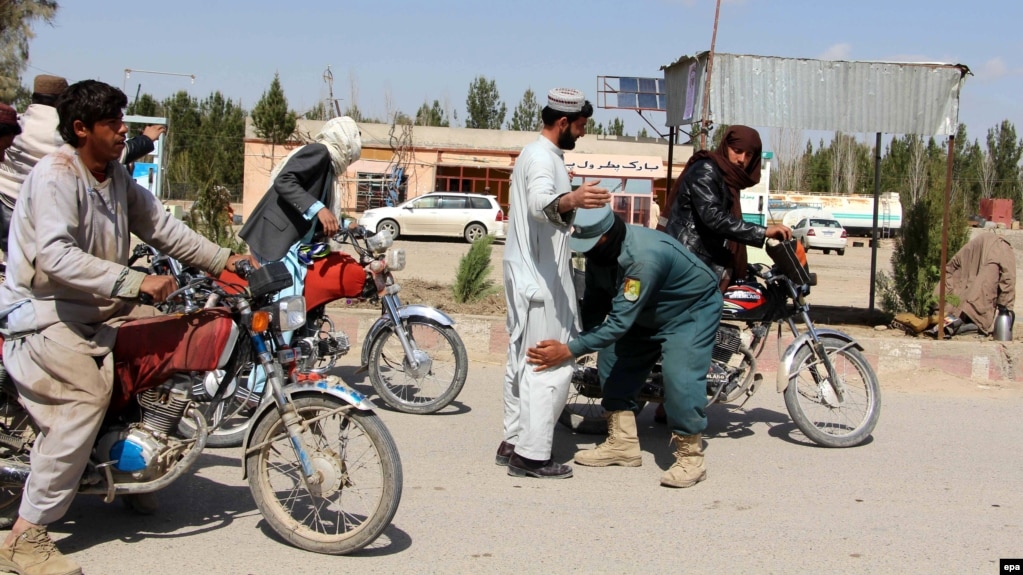 An Afghan security official checks people at a checkpost in Helmand.