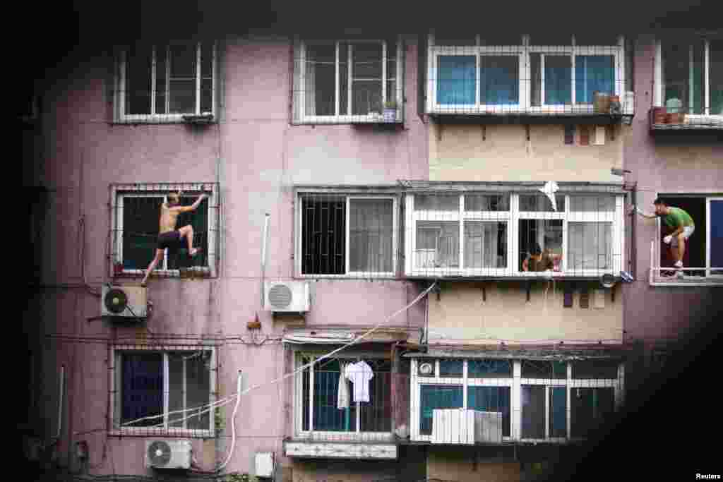 A man (left) climbs outside a window with a knife as his mother (center) and a plainclothes policeman look on, in Anshan, Liaoning Province, China. The man held his mother captive in his apartment before climbing out of the window and threatening to cut himself. After several hours, he was controlled by police who managed to enter the house from another window with the help of his mother. (Reuters)