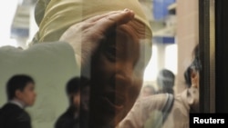 Старушка-казашка всматривается в окно помещения, где идет суд над жителями Жанаозена, обвиненными в участии в беспорядках в декабре 2011 года. Актау, 27 марта 2012 года.
