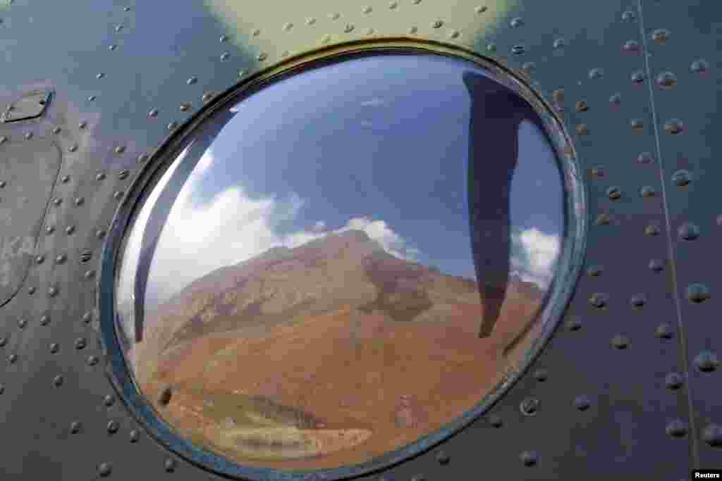 Vladimir Putin Peak, measuring 4,446 meters (14,586 feet) above sea level, is reflected in the window of a helicopter in the Tian Shan mountains.