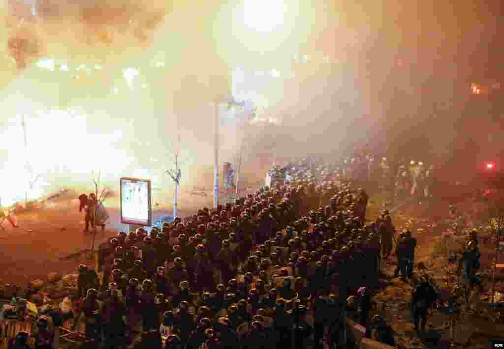 Riot police stand in front of burning barricades surrounding Independence Square.