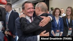 Former German Chancellor Gerhard Schroeder (left) hugs Russian President Vladimir Putin at the opening of the soccer World Cup in Moscow in 2018. 