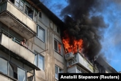 A man watches a neighbor's apartment burn after a drone strike in Druzhkivka on June 22.
