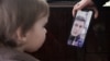 Ihar Losik's wife, Darya Losik, shows a photo of him to their young daughter in January 2023.