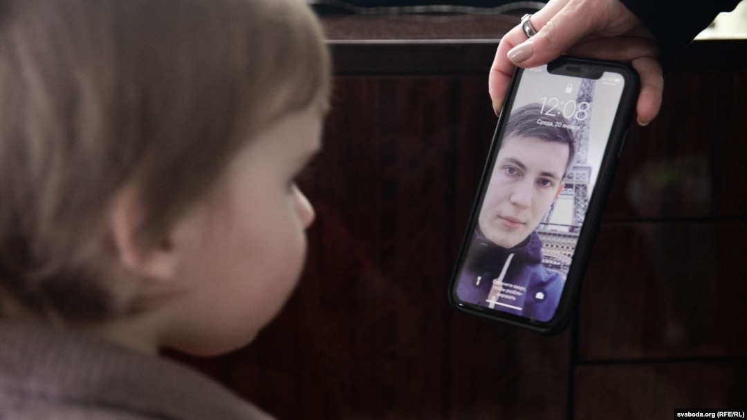 Ihar Losik's wife, Darya Losik, shows a photo of him to their young daughter in January 2023.