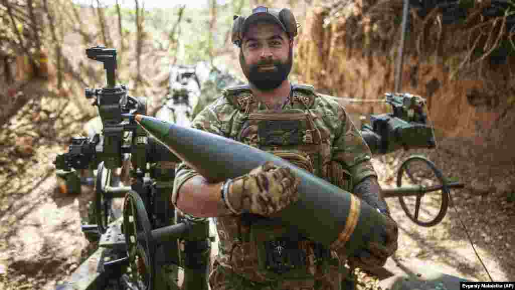 A Ukrainian soldier going by the call sign "Bronson" of the 148th Artillery Brigade carries a 155mm shell in front of M777 howitzer at a front line in the Zaporizhzhia region.