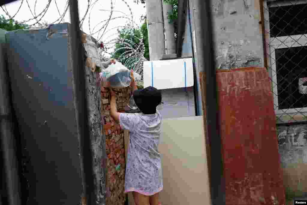 Жінка отримує їжу всередині житлового комплексу, в якому було запроваджено жорсткі заходи боротьби з вірусом та який оточили колючим дротом після нового спалаху коронавірусної хвороби (COVID-19), в районі Фенгтай, в Пекіні, Китай