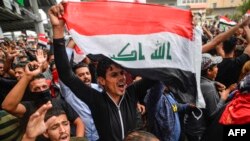 An Iraqi protester chants slogans as he marches with a national flag during an anti-government demonstration in the central holy shrine city of Najaf on October 25, 2019