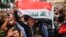 An Iraqi protester chants slogans as he marches with a national flag during an anti-government demonstration in the central holy shrine city of Najaf on October 25, 2019