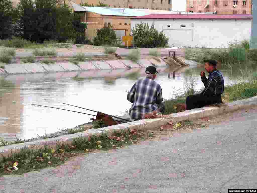 Iki ýaşuly derýanyň kenarynda balyk tutýar.