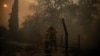 Firefighters spray water on a burning residential area during a wildfire near Lege Cap Ferret, southwestern France on July 23, 2026.
