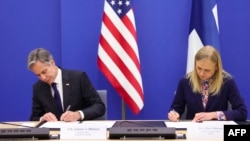 U.S. Secretary of State Antony Blinken (left) and Finnish Foreign Minister Elina Valtonen sign a memorandum of understanding on combating disinformation in Brussels on April 4. 