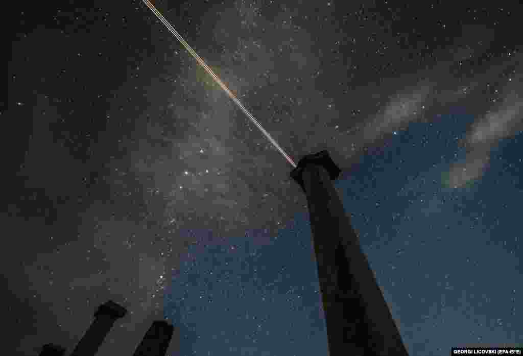Un avion traversează cerul brăzdat de ploaia de meteori din acest an. Fotografia a fost realizată în dreptul sitului arheologic Stobi, de lângă Negotino, Republica Macedonia de Nord, la data de 12 august 2021. Ploaia de meteori Perseid apare în fiecare an când Pământul trece prin resturile și praful lăsat în urmă de cometa Swift-Tuttle.