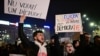 People protest in the front of the Palace of the Parliament at the Victory square in Bucharest, Romania, on November 27, 2024, with banners reading (L) "Do not vote for a dictator", after the surprise win of a far-right candidate in the first round of the