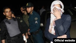 A photo purportedly showing Hall Talayan (right, covering face), whom "Iran" daily said was detained on the Armenian-Iranian border on suspicion of spying.