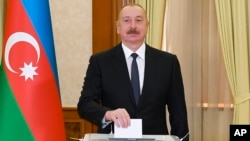 Азербайджанский лидер Ильхам Алиев опускает бюллетень в урну на избирательном участке в городе Ханкенди, 7 февраля 2024 года