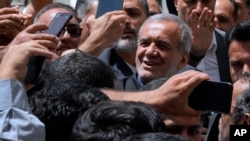 Масуд Пезешкијан е пречекан од неговите поддржувачи додека пристигнува да гласа на избирачкото место во Шахр-е-Кодс во близина на Техеран, Иран, петок, 5 јули 2024 година. 