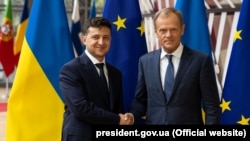 Volodymyr Zelenskiy (left) and Donald Tusk shake hands in Brussels on June 5.