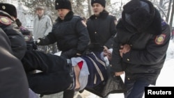Полицейлер үкіметке наразылық жиынына шыққан белсендіні әкетіп барады. Алматы, 25 ақпан 2012 жыл.