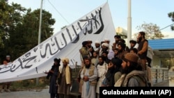 Боевики движения "Талибан" позируют для фотосъемки во время поднятия флага в Газни, Афганистан. 15 августа 2021 год