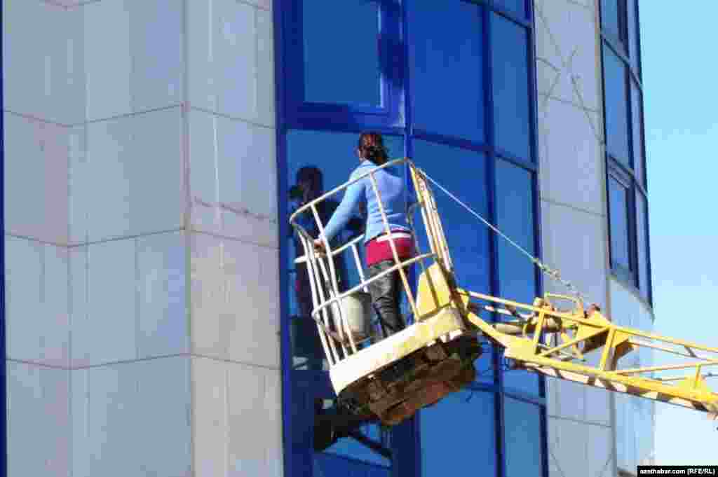 Gyz bir binanyň aynalaryny ýuwýar